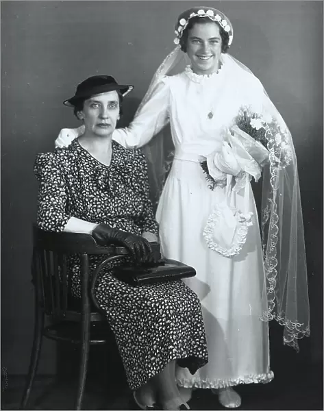 Woman sitting next to a girl dressed for her first communion