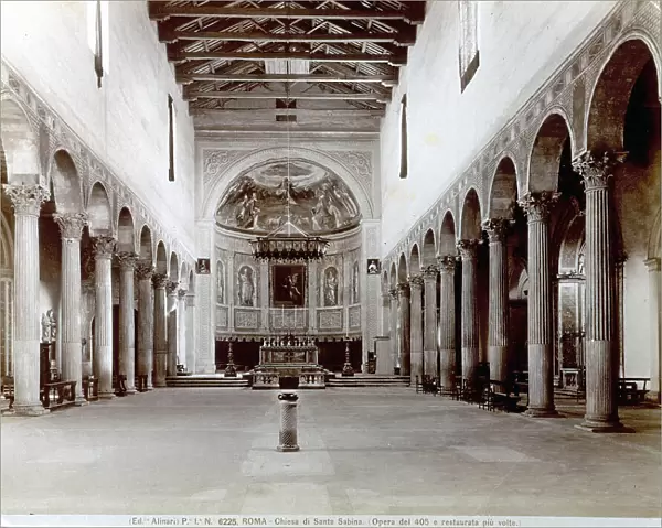 The nave of the Church of Santa Sabina, in Rome. Corinthian columns supporting arches are at the sides of the nave. In the background the apse conch with frescoes by Zuccari, preceded by the bishop's throne. The ceiling is an open timber covering from which a large chandelier hangs