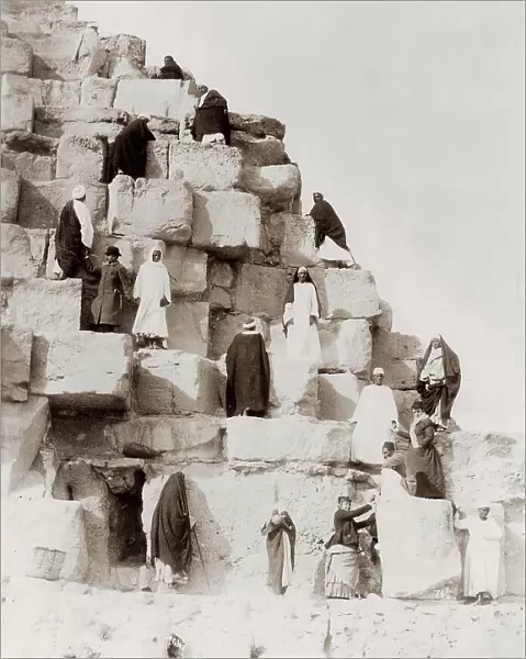 Egyptian men and tourists on the steps on a pyramid