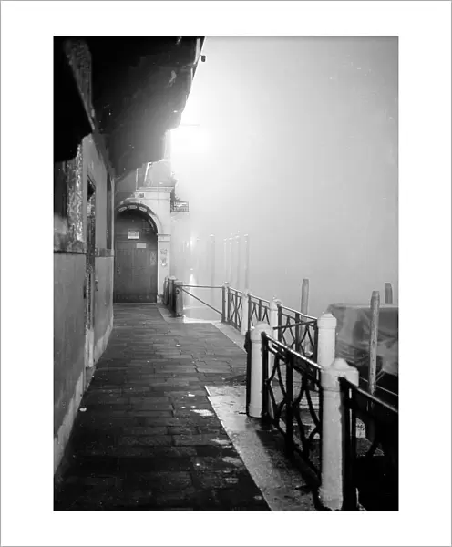 Nocturnal, street-level view of a building in Venice, deserted and shrouded by the evening fog
