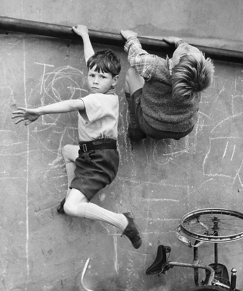 Two boys climbing wall on a Balham street, SW London
