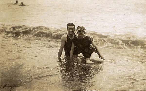 Couple sitting in surf - British seaside candid photograph