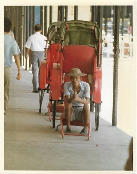 Elderly Chinese man in an empty red rickshaw