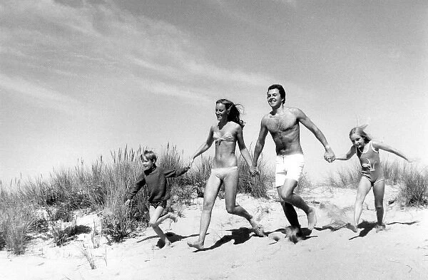 Family running across sand dunes