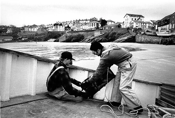 Fishermen bait a lobster pot, Newquay, Wales
