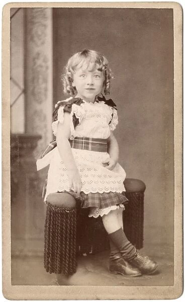 Little Victorian girl in lacy dress with tartan trimmings