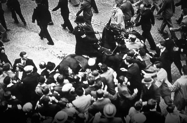 Policeman on horseback with an unruly crowd