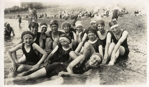 Thirteen seaside bathers in swimming costumes and caps
