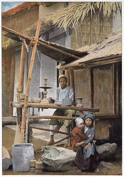 Vietnamese wood worker and his family outside their home. Date: 1890s