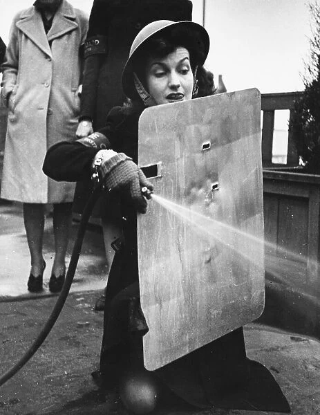 West End stage and film star, Miss Judy Campbell, learns how to use a stirrup pump