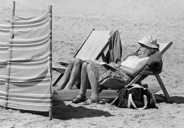 Woman sleeping on deck chair on Tenby Beach, Wales