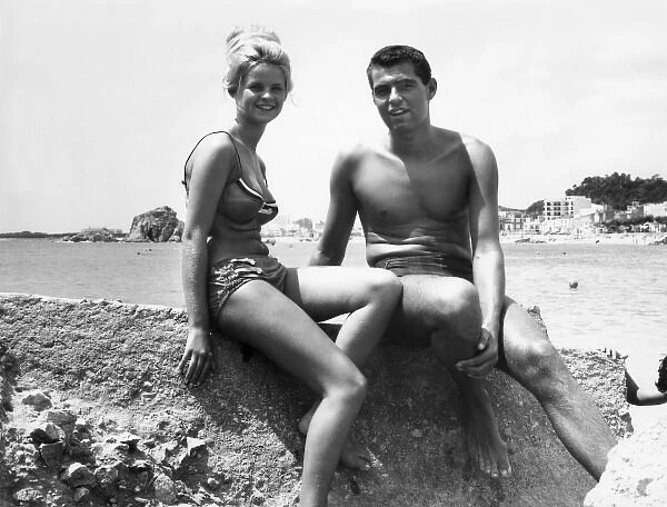 Young couple sitting on a rock at the seaside