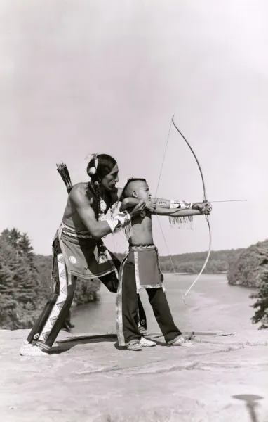 Young Native American Indian boy learning to shoot his bow