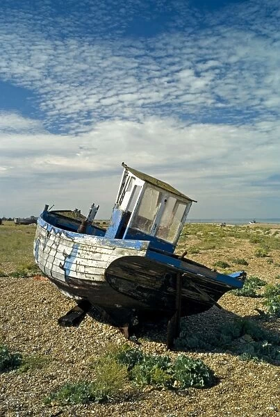 Abandoned Boat on shore - Dungeness, Kent. The beach at Dungeness looks like a dumping ground, but geologists are fascinated by the action of tides and wind on this extreme corner of Kent