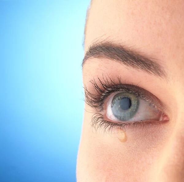 Close-up of a womans blue eye with a tear-drop