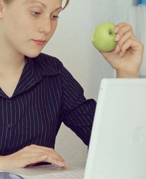 Snacking. MODEL RELEASED. Snacking. Young woman eating an apple at her