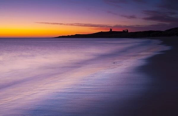England, Northumberland, Embleton Bay. A colourful display of pre-dawn colours relected upon the wet sands of Embleton Bay, overlooked by the dramatic ruins of