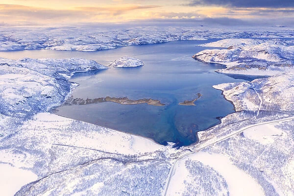 Aerial view of Norwegian County Road 98 along snowy mountains above Laksefjorden, Lebesby