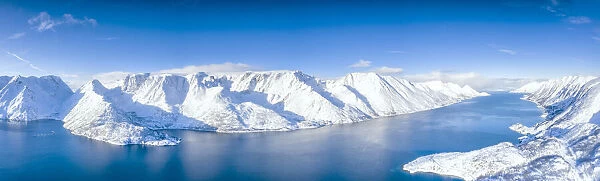 Aerial view of snow capped mountains and fjord during the cold arctic winter, Oksfjord