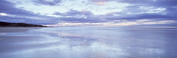Beach at Alnmouth at dusk with dramatic clouds reflecting in wet sand at low tide