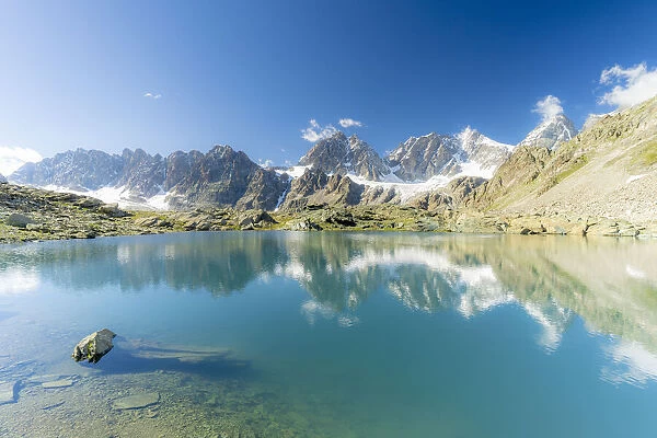 Bernina Group mountains mirrored in the clear water of Forbici lake, Valmalenco