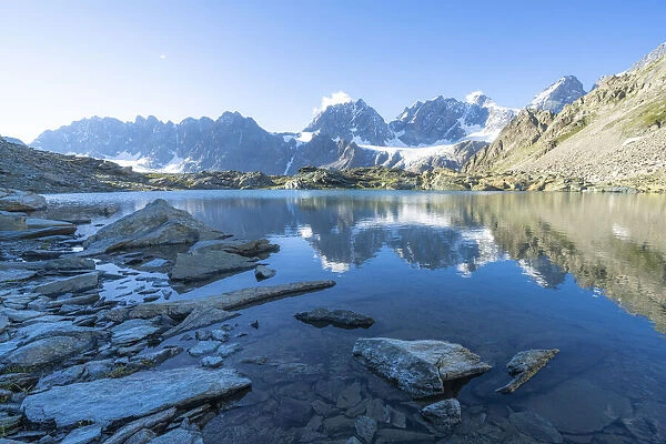 Bernina Group reflected in the clear water of Forbici lake at dawn, Valmalenco