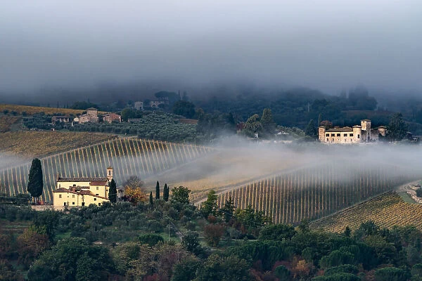 Castello di Gabbiano across a misty valley, church in foreground, San Casciano, Tuscany