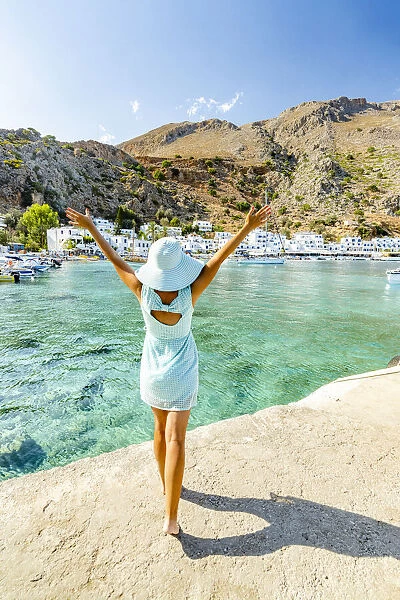 Cheerful woman with sun hat admiring the village of Loutro and crystal sea, Crete island, Greek Islands, Greece, Europe