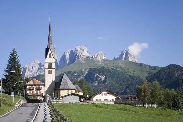 A church in the village of Alba with the rugged peaks of the Sassolungo in the distance
