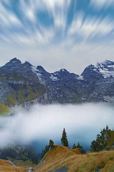 Clouds in the sky above lake Oeschinensee covered by fog, Bernese Oberland, Kandersteg