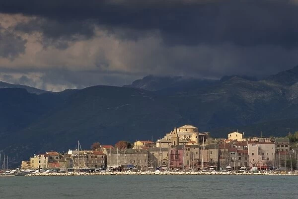 Dark clouds over hills and the skyline of the town of St. Florent on Cap Corse on the island of Corsica, France