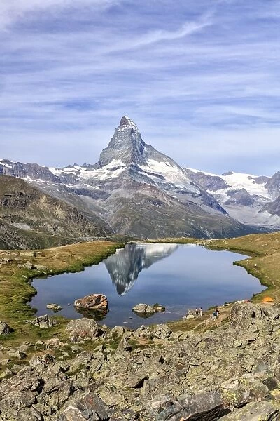 Hikers admire the Matterhorn reflected in Lake Stellisee, Zermatt, Canton of Valais