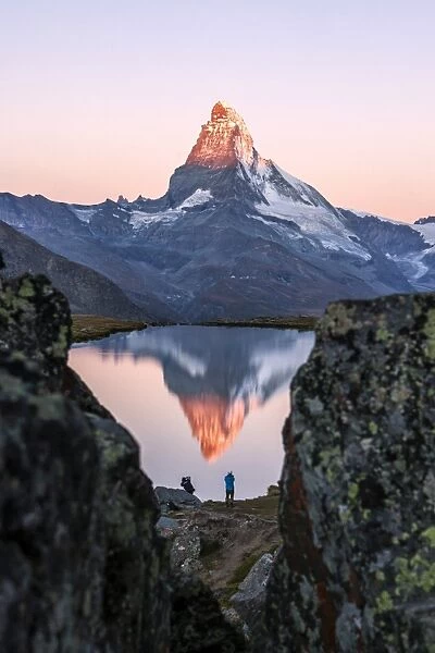 Hikers admire the Matterhorn reflected in the Stellisee at sunrise, Zermatt, Canton of Valais