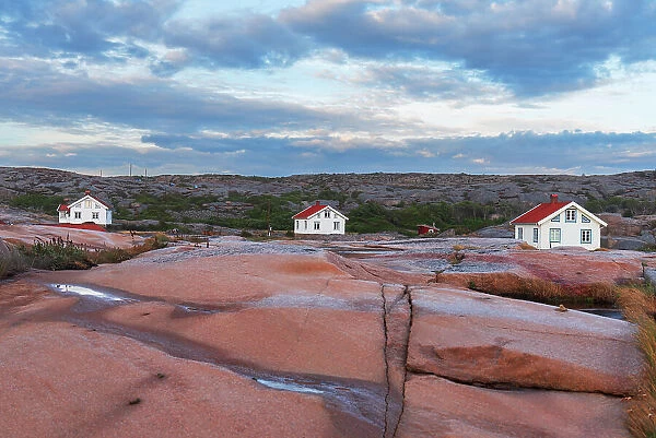 Three isolated houses on red granite island at dusk, Bohuslan, Vastra Gotaland, West Sweden, Sweden, Scandinavia, Europe