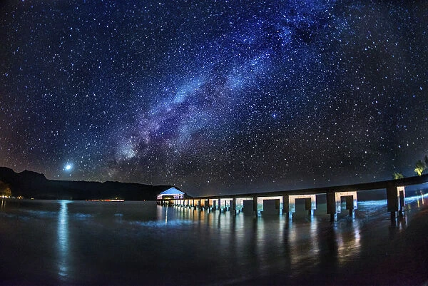 The Milky Way and Venus rise over the Hanalei Bay with the Hanalei Pier in the foreground
