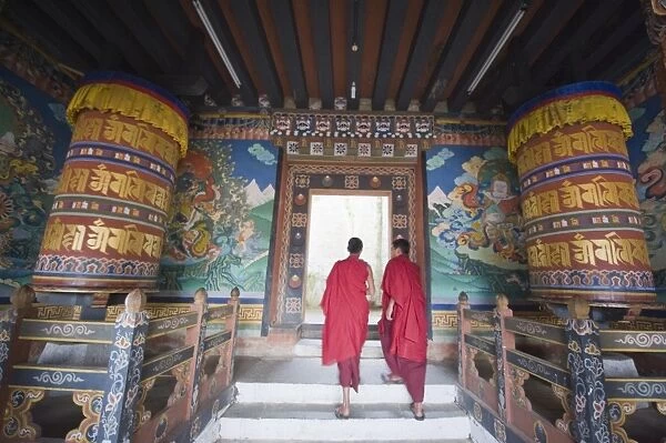 Monks walking between prayer wheels at Trongsa Dzong (Chokhor Raptentse) dating from 1648