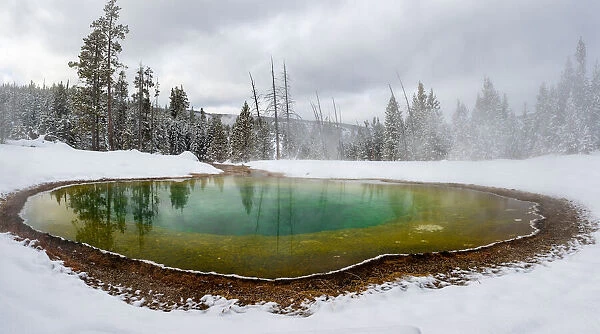 Morning Glory pool hot spring in the snow with reflections, Yellowstone National Park