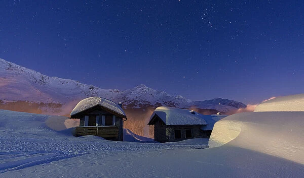 Mountain huts covered with snow during a winter starry night, Andossi, Madesimo