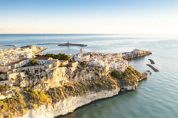 Old town of Vieste perched on cliffs at sunrise, aerial view, Foggia province