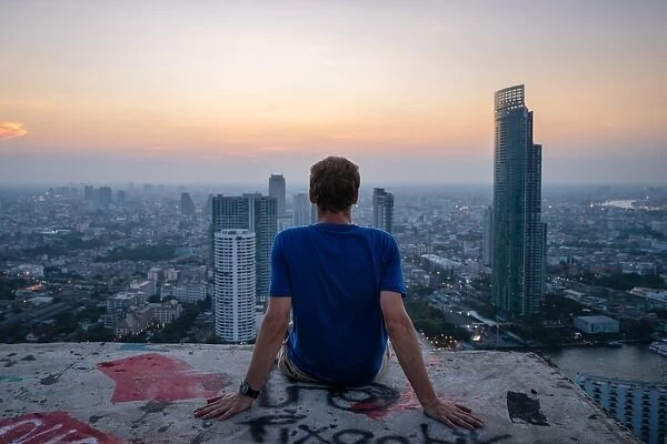 A single man watching sun set over city skyline at dusk, Bangkok, Thailand, Southeast Asia