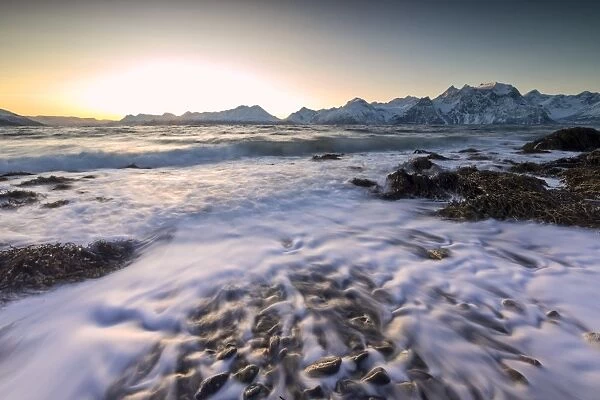The sunset light reflected on the waves of cold sea crashing on the rocks, Djupvik