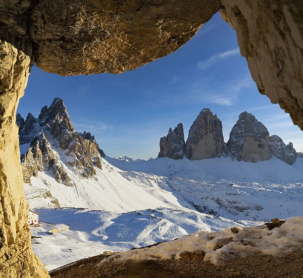Sunset over the snow capped Tre Cime di Lavaredo and Monte Paterno seen from rock cave