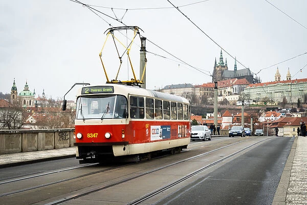A traditional red tram crosses Manesuv most (bridge) with St