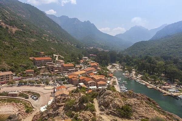 The typical village and harbor of Porto immersed in the green vegetation of the promontory