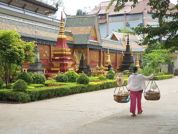 Woman carrying baskets over her shoulders outside a temple in Siem Reap, Cambodia