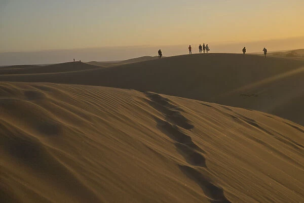 Young people watching the sunset at Maspalomas sand dunes, near Playa de los Ingleses, Gran Canaria, Canary Islands, Spain, Atlantic, Europe