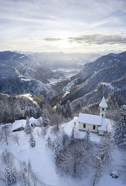 Aerial view of the Silvestri church and the Scalve valley after a winter sunrise