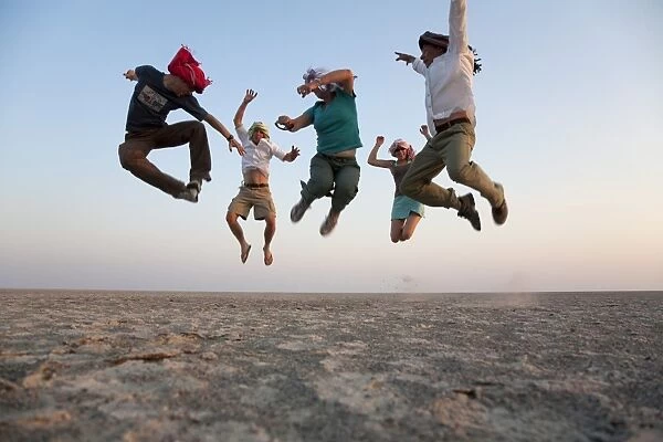 Botswana, Makgadikgadi. A family jump high in the air above the Makgadikgadi salt pans