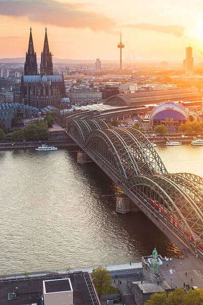 Hohenzoller Bridge over River Rhine and Cologne Cathedral at sunset in Cologne city