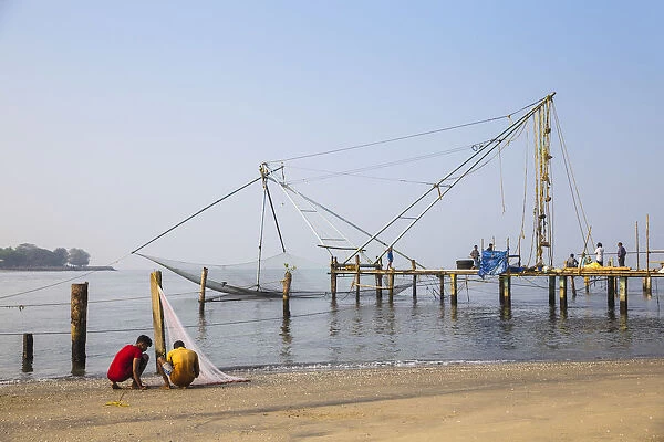 India, Kerala, Cochin - Kochi, Fishermen untable thir nets inthe background are Chinese